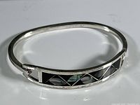 Front view of oval sterling silver bracelet with geometric black and abalone shell inlay detail