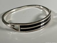 Close-up photo of the front of the silver bracelet showing black enamel inlay and geometric design.