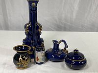 Five-piece cobalt blue and gold porcelain set including violin vase, small jar, mini vase, oil vessel, and covered trinket dish.