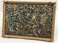 Full front view of the rectangular vintage frame showing the scalloped edges and gold paint finish, holding a decorative marbled paper replacement.