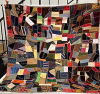 Full front view of the large vintage patchwork quilt showing the array of multicolored fabric pieces and hand-stitched seams.