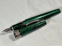 Pen uncapped showing barrel, section, nib and cap laid beside barrel