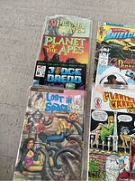 Photo showing front covers of multiple comic books in lot including Planet of the Apes, Judge Dredd, Lost in Space, Flaming Carrot Comics