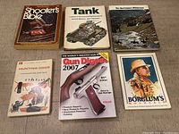 Six outdoors and firearms related books shown on a wooden floor surface