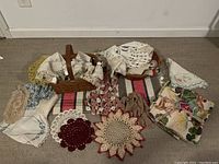 Top view of lot showing multiple woven baskets, assorted crocheted doilies, and various fabric pieces laid out on a blanket.