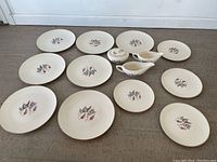 Full set of dinnerware including plates, gravy boats, and sugar bowl arranged on floor.