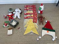 Various Christmas decorations displayed on floor including plush figures, star ornaments, hat, and smaller decorations.