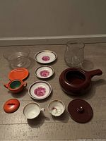 Wide view showing full set of kitchen items including plates, cups, compote, jar, casserole, and orange ceramic dish