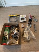 Photo of assorted plumbing accessories laid on floor including valve kit, hose connector, drain traps and strainers.