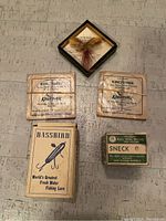 Top down photo of the entire lot showing Bassbird lure box, Westphal's Bass Bug lure in display box, two Kingfisher leader line packages, and Sneck hooks box.