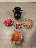 Top view of all five pincushions and decorative urn arranged on a neutral surface