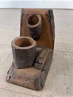 Wooden cigarette striker shown from an angled side view, displaying the two cylindrical holders and the matchbox holder attached to the base.