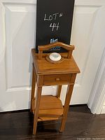 Full front view of small antique wooden table showing top, drawer, inkwell holder and lower shelf