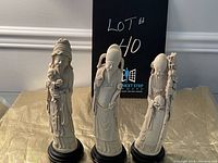 Full front view of the three Japanese wise men figurines on round black bases against a beige cloth background
