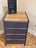 Front and angled view of a 4-drawer steel grey cabinet with wood top, showing drawer pulls and condition.