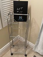 Front view of the chrome basket storage cart with three wire mesh baskets and casters