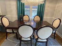 Full view of the rectangular dining table with extension leaf in place surrounded by six chairs