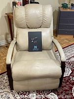 Front view of creamy colored leather chair with wooden armrests, showing padded backrest and seat cushion.