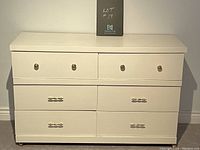 Front view of the plain white low boy dresser showing the arrangement of six drawers and two types of drawer pulls.