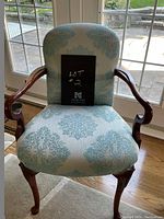 Front view of the queen anne style occasional chair showing turquoise patterned upholstery and wooden arms and legs.