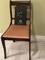 Front view of vintage wooden accent chair with pink upholstered seat and lyre back, showing slight curve of legs and overall condition.