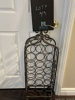 Full front view of the metal wine rack with circular bottle holders and decorative floral metalwork at the top