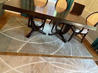 Full view of the wool rug under a dining table showing starburst pattern in cream.
