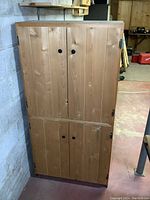Front view of the wooden 4-door storage cabinet showing natural wood finish and black round knobs.