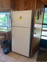 Front view of refrigerator on wood-paneled kitchen floor