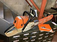 Side view of Stihl chainsaw on workbench with bar cover and manual