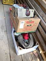 Three cardboard boxes stacked, each containing various ratchet tie down straps and hold downs.