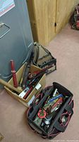 Overview of two tool totes and a box, containing various hand tools such as pipe wrenches, mallets, hand rasps, and other tools.