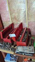 Photo showing two red metal toolboxes open with trays holding assorted hand tools, sockets, wrenches and ratchets inside.