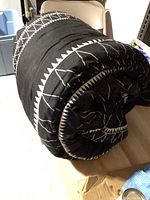 Rolled black and white printed XL twin comforter placed on a table.