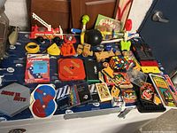 Overview of assorted toys and games including Fisher Price fire truck, Rubik's Cube, card decks, and boxed games