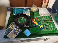Overall photo showing the collection of casino game items including the roulette wheel, cloth, chips, and betting cards.