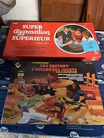 Photo showing Super Aggravation board game box alongside Woodworkers Toy Factory wooden set box with toys.