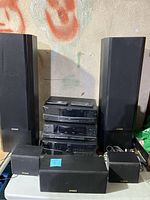 Full view of the 5 speaker surround sound system with all speakers and stereo components arranged together on a table.