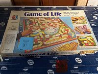 Original box for the Game of Life, showing top cover and box art with a hand spinning the wheel and colorful board pathways.
