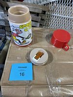 Photo showing the side of the Aladdin thermos with Goofy playing baseball and the beige screw lid removed. The red thermos cup lid is placed nearby along with the inner stopper piece.