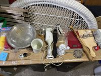 Wide view of the kitchen lot items on a table including aluminum pot, mixers, scale and accessories