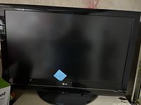 Front view of LG 42 inch LCD TV powered on, black bezel, model label on front.