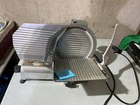 Photo showing the electric meat slicer from the side with serrated blade and food carriage