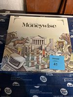 Front side of Financial Post Moneywise board game box with thematic financial illustrations including animals and stacks of money.