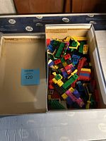 Open shoe box with assorted vintage LEGO bricks showing variety of colors and piece types.