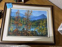 Full view of framed painting showing lake, trees and mountains