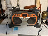 Full front view of the Rigid Race Stereo portable radio showing the frame, handle, dual speakers, and control panel.