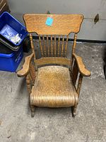 Front view of the wooden rocking chair showing seat, back with spindles and wide armrests.