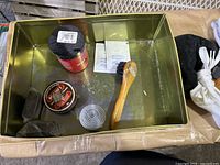 Photo showing metal tray with shoe polish tins, brush, black sponge, shoehorn, and some small items inside.