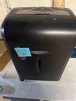 Front view of black Dynex paper shredder placed on a table, showing overall shape and design